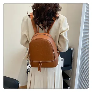Detail of brown faux leather backpack featuring letter embossing and a daisy charm