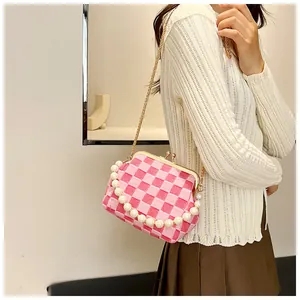 Detail of pink plaid shell bag with pearl handle and golden metal clasp closure
