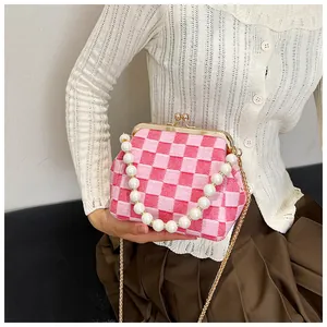 Detail of pink plaid fabric texture with large pearl handle and gold clasp on a shell bag