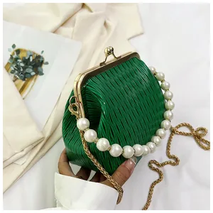 Detail of green pleated velvet shell bag with pearl handle and golden chain strap