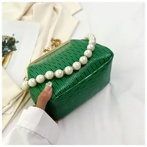 Detail of green pleated shell bag with large pearl handle and gold metal clasp frame