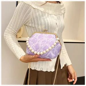 Detail of light purple shell bag with pearl handle and golden chain on model's shoulder