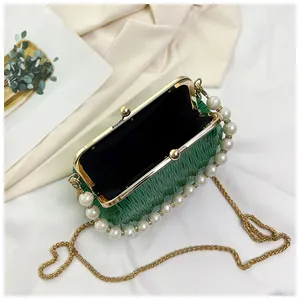 Detail of green pleated shell bag showing pearl handle, gold frame, and chain strap