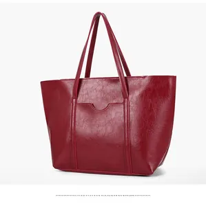 Side view of a deep red textured faux leather tote bag with elegant wavy pocket detail