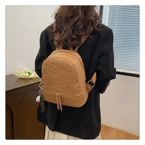 Close-up of brown textured leather backpack featuring embossed letters on back of model