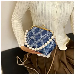 Detailed close-up of blue denim shell bag with pearl handle and golden clasp closure