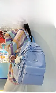 Detail of lavender canvas backpack with blue straps and plush bear keychain
