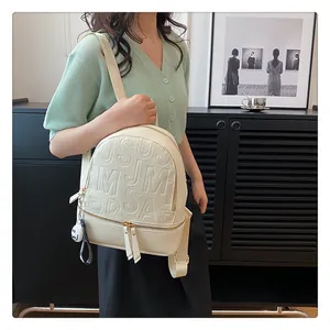 Close-up of cream leather backpack with embossed letters and ghost charm detail