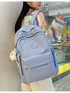 Detail of light blue waterproof nylon backpack featuring side straps and a plush toy charm