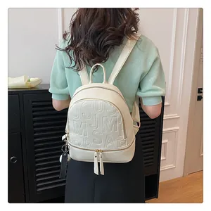 Close-up of creamy white backpack featuring 3D embossed letters and荔枝 texture detail