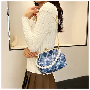 Blue denim shell bag featuring a pearl bead handle and metallic gold chain strap