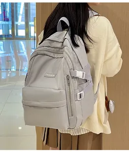 Detail view of a large light grey nylon backpack with multi-layer zippers and fashion tag