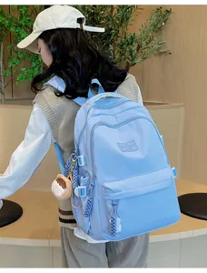 Detail view of light blue nylon backpack with cute plush charm and adjustable side straps
