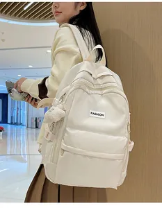 Detail of cream white waterproof nylon backpack with plush bear and multi-pocket design