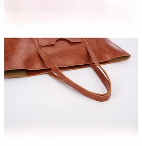 Detail display of brown faux leather tote bag showing ergonomic handles and stitching