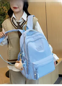 Detail of light blue nylon backpack featuring brand patch and cute plush monkey charm