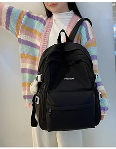 Detailed view of black nylon backpack featuring a plush bear charm and side adjustment buckles
