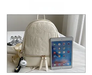 Detail of waterproof beige leather backpack with embossed letters and a smiley charm