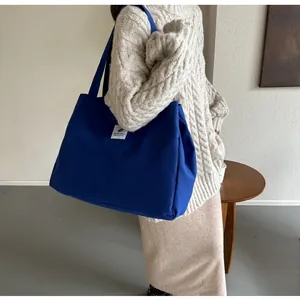 Détail du grand sac cabas en toile bleue avec écusson blanc et anses longues