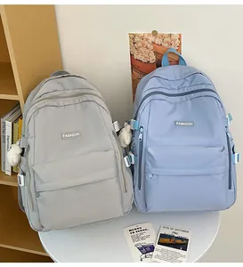 Detail view of large capacity school backpacks in light grey and light blue with plush charm
