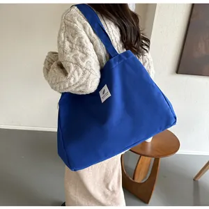 Détail du sac fourre-tout en toile bleu roi avec étiquette blanche et texture de bandoulière