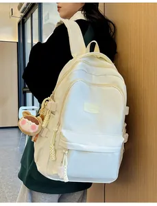 Detail of minimalist cream student backpack with cute plush charms and multiple pockets