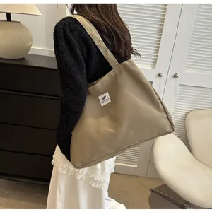 Grand sac cabas en toile kaki avec étiquette tissée présenté dans une scène d'intérieur