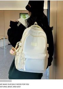 Beige minimalist school backpack for girls with cute charms shown on a model side view