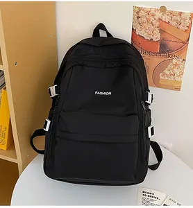 Detail of black nylon backpack featuring white buckles and Fashion label on the front