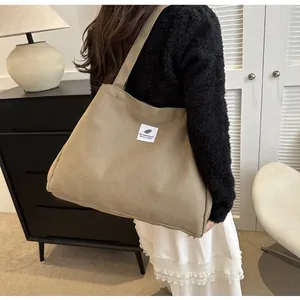 Vue détaillée d'un grand sac fourre-tout en toile kaki porté à l'épaule par un mannequin