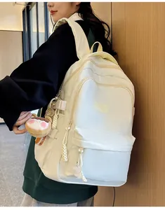 Detailed side view of beige nylon backpack with adjustable buckles and plush charm