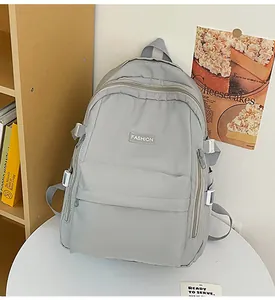 Macro view of light gray nylon backpack showing front zip pocket and fashion label