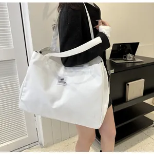 Grand sac cabas en toile blanche avec écusson texte porté dans un bureau moderne