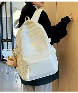 Detailed side view of a white minimalist nylon backpack with cute cartoon girl pendant detail