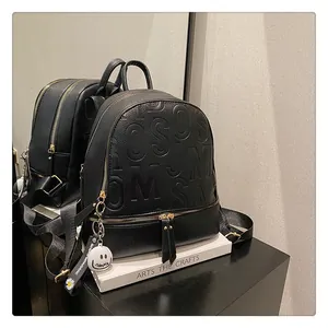 Detail of black pebbled leather backpack with gold zippers and decorative daisy charms