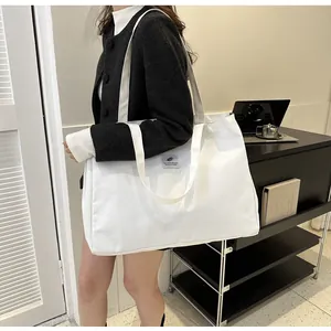 Détail d'un grand sac cabas en toile blanche porté par un mannequin au bureau