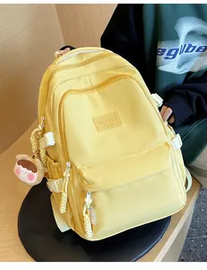 Detailed view of yellow school backpack with multiple pockets and cute plush pendant charm