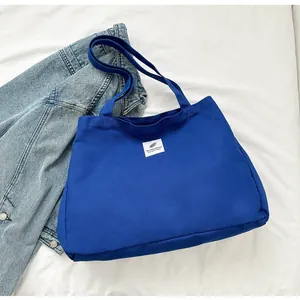 Vue détaillée du sac cabas en toile bleu Klein avec étiquette blanche et bandoulière