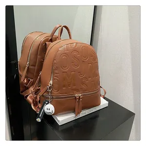 Close-up of brown litchi grain leather backpack with embossed letters and metal zipper