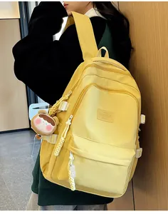 Side view of a bright yellow nylon school backpack with a cute bear charm for students
