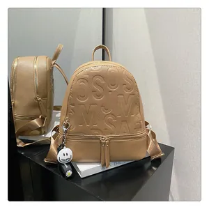 Detail of khaki faux leather backpack with embossed letters and a daisy charm accessory