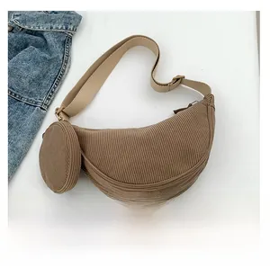 Detail view of brown corduroy crescent bag with small round coin purse and smartphone for scale