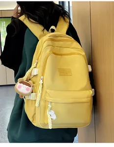 Detail of yellow school backpack featuring adjustable white side buckles and plush pendant