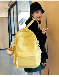 Detail of bright yellow nylon school backpack featuring side straps and a cute plush bear