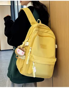 Detail view of yellow school backpack with durable side buckles and plush hanging charm