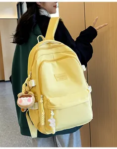 Close-up of vibrant yellow minimalist backpack with cute bear and dog charms on a model