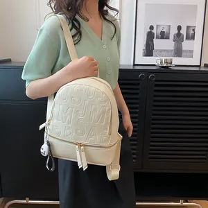 Waterproof cream leather backpack with embossed letters and plush charm on black background