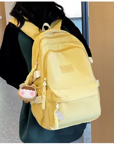 Detail view of the yellow nylon backpack with multi-zipper pockets and bear charm