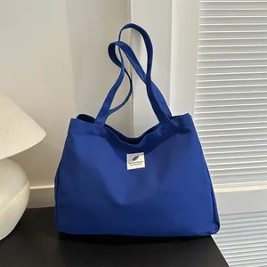 Grand sac cabas en toile bleue avec bandoulières et écusson plume blanc