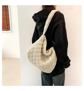 Detail of a large off-white corduroy tote bag with diamond quilting shown on a model